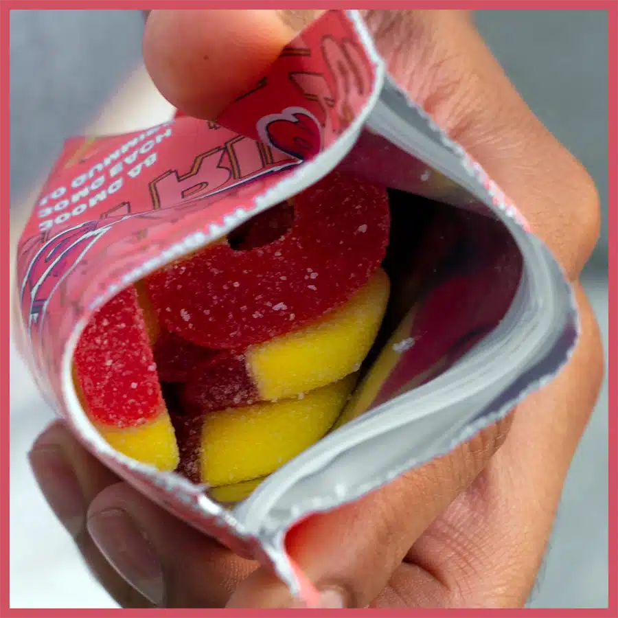 An open bag of delta munchies peach rings showing the pink and yellow color and the size of the edibles.